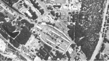 An aerial photograph of Zwelihle in 1967 showing the blunted elliptical shape, the dense growth of tress and the separate inward looking nature of the site with buildings grouped around a central space. The industrial work area is north in the photog