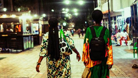 two women walking down a street in Kigali, Rwanda, at night. Photo: shimo-yann-2W7OWirnmQg-unsplash
